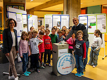 Gruppenbild, im Hintergrund die Plakate, im Vordergrund die Wahlurne Gruppenbild, im Hintergrund die Plakate, im Vordergrund die Wahlurne