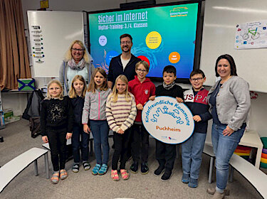 Gruppenbild mit Kindern, Rektorin, Trainer und der Vorsitzenden des Elternbeirats. Die Kinder halten ein großes Log der Kinderfreundlichen Kommune Puchheim. Gruppenbild mit Kindern, Rektorin, Trainer und der Vorsitzenden des Elternbeirats. Die Kinder halten ein großes Log der Kinderfreundlichen Kommune Puchheim.