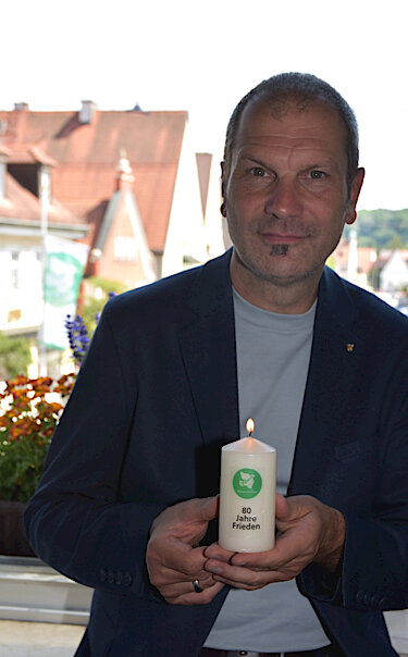 Christian Götz, Oberbürgermeister von Fürstenfeldbruck, hält die Friedenskerze in der Hand