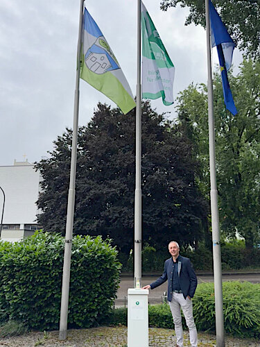 Erster Bürgermeister Seidl mit der Friedenskerze vor den Flaggen von Puchheim, der Mayors for Peace und der Europäischen Union