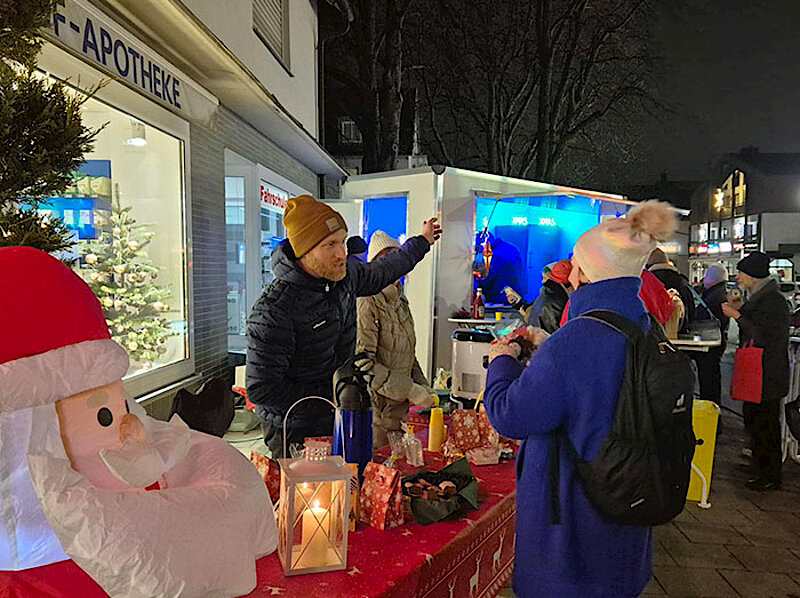 Adventlich geschmückter Tisch vor der Apotheke und Besucher:innen Adventlich geschmückter Tisch vor der Apotheke und Besucher:innen