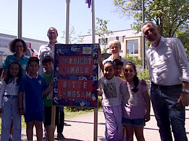 Gruppenbild mit allen Beteiligten und dem Plakat vor der Grundschule Süd Gruppenbild mit allen Beteiligten und dem Plakat vor der Grundschule Süd