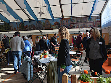 Besucherinnen und Besucher gehen im Festzelt um die Tische. Besucherinnen und Besucher gehen im Festzelt um die Tische.