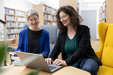 Zwei Frauen schauen gemeinsam auf einen Laptop in der Stadtbibliothek Puchheim